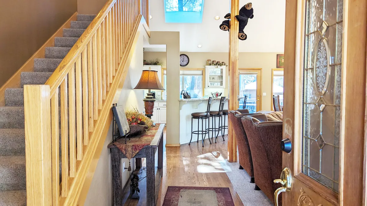 A welcoming interior view featuring a staircase, bar area, and comfortable living room seating. The layout suggests ample space for relaxing, entertaining, or gathering with family and friends, suitable for game nights or movie marathons.