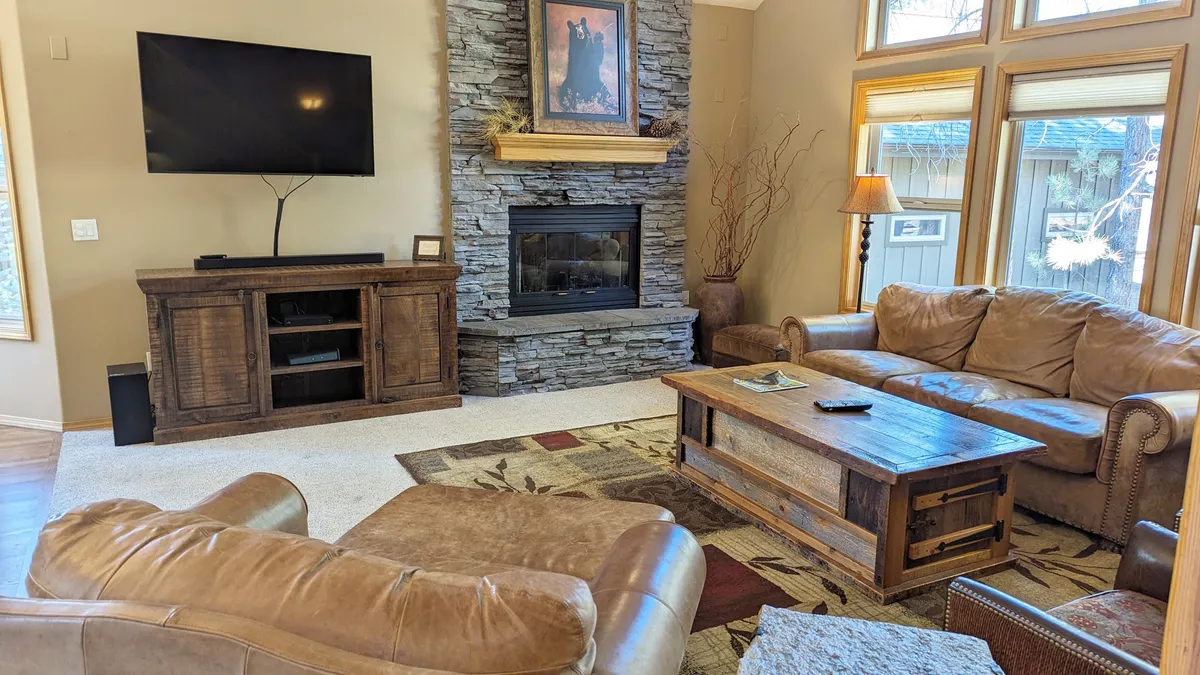 A cozy living room centered on a striking stone fireplace, with plush leather sofas and a large TV, perfect for unwinding after a day of exploration. The space is intimate yet inviting, ideal for evenings spent together.