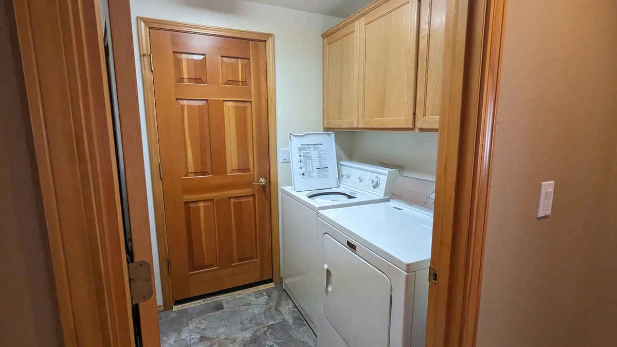 A practical mudroom featuring a washer, dryer, wooden door, and cabinets—an essential space for cleaning up after outdoor adventures with pets.